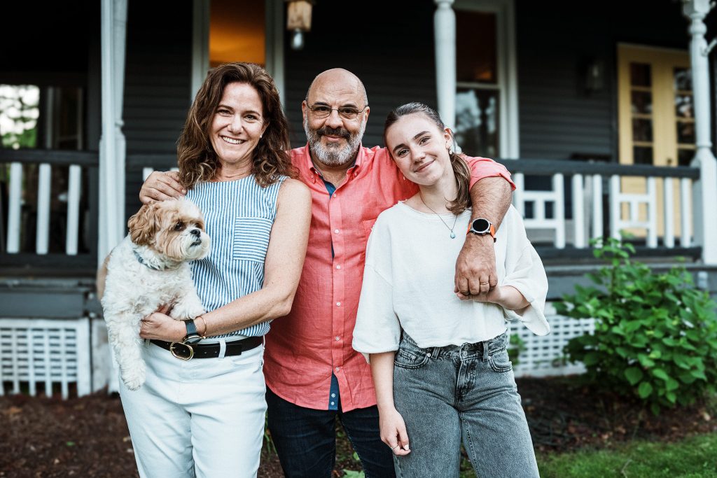 family with a dog in front of a house
